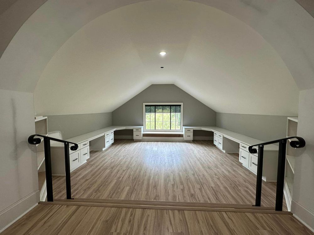 An empty attic with wooden floors and stairs leading to it.