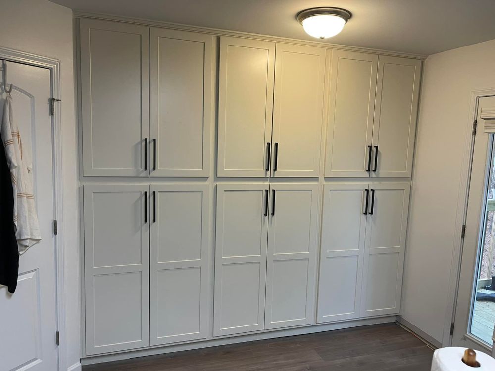 A room with a lot of white cabinets and a toilet.