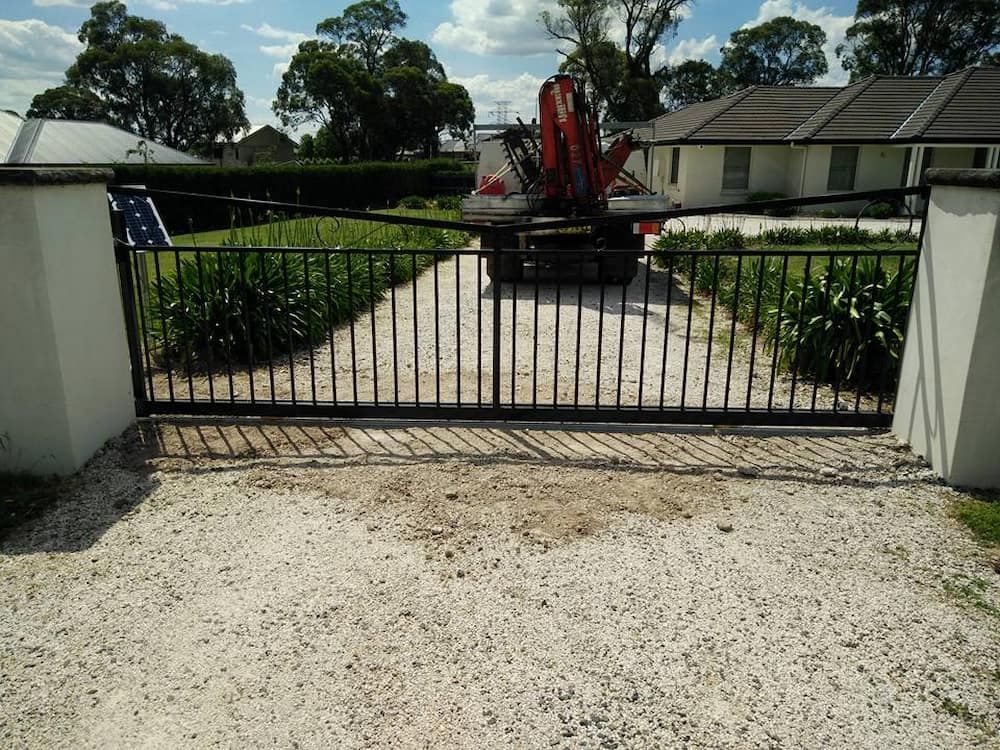 A Sliding Gate is Open to a Gravel Driveway Leading to a House — Southern Gate Automation in Picton, NSW