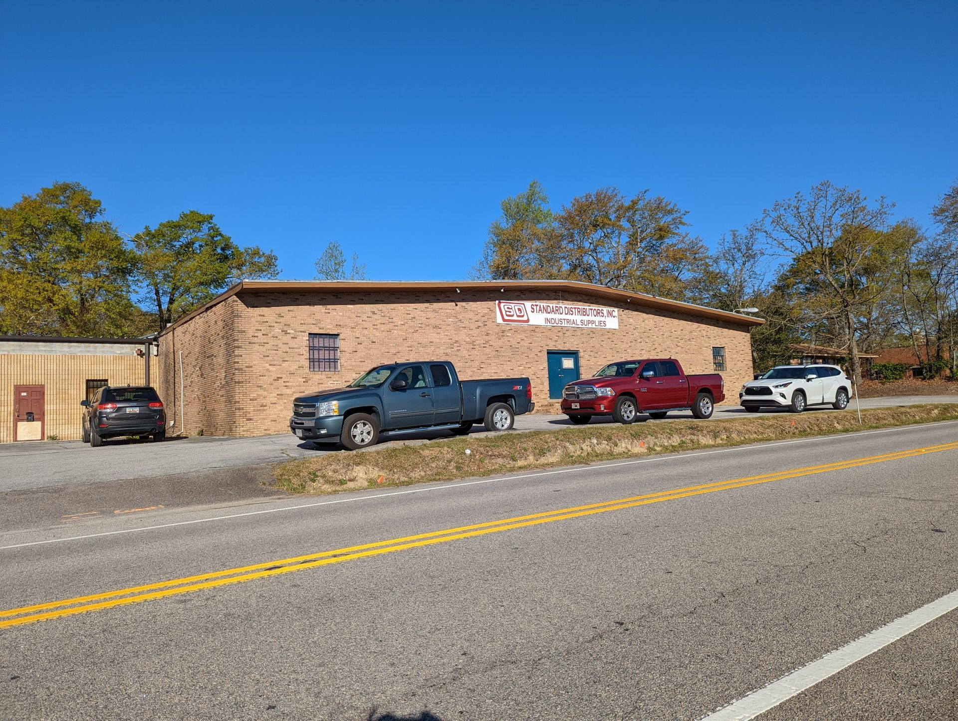Brick roadside building with parked pickup trucks under a clear blue sky