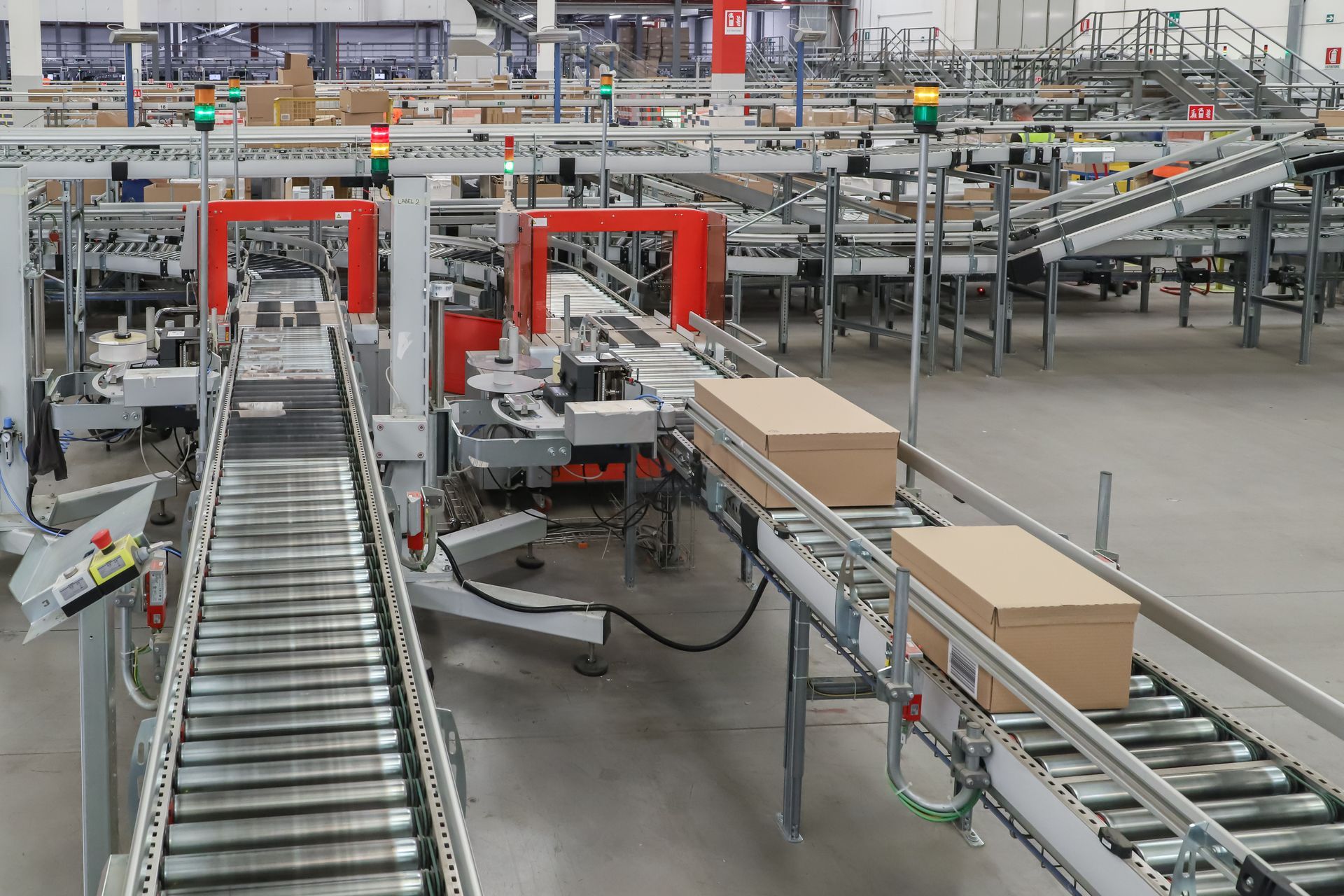 Automated warehouse conveyor belts moving cardboard boxes through a packaging line