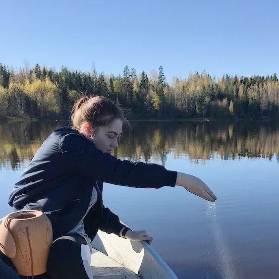 A woman is sitting in a boat on a lake.