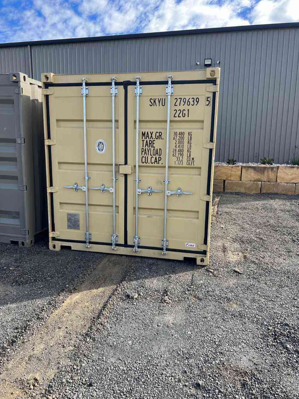 A Shipping Container is Sitting in a Gravel Lot in Front of a Building — Toowoomba Container Hire & Sales in Wilsonton, QLD