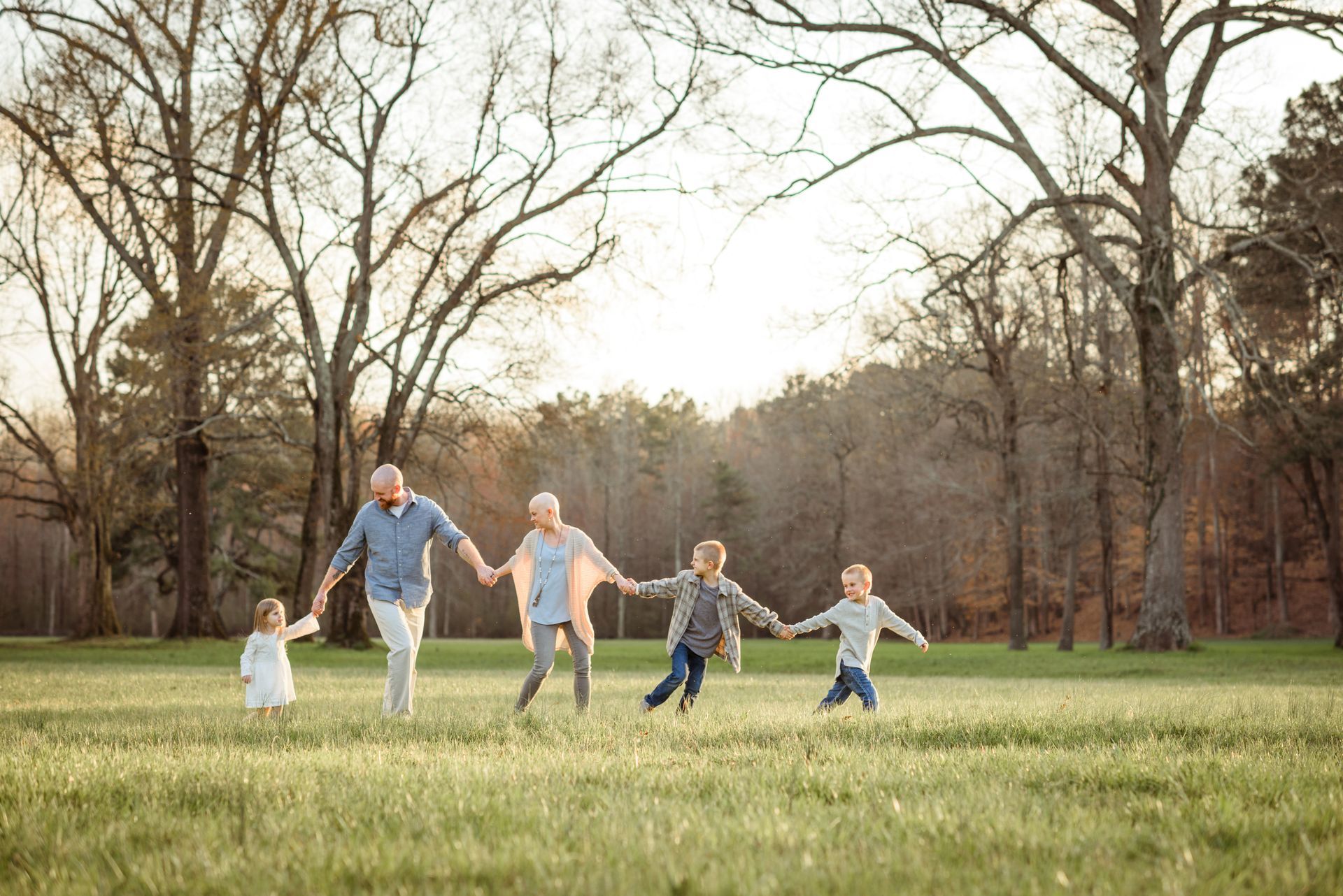 A family is holding hands and running in a field.