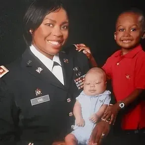 A woman in a military uniform is holding a baby
