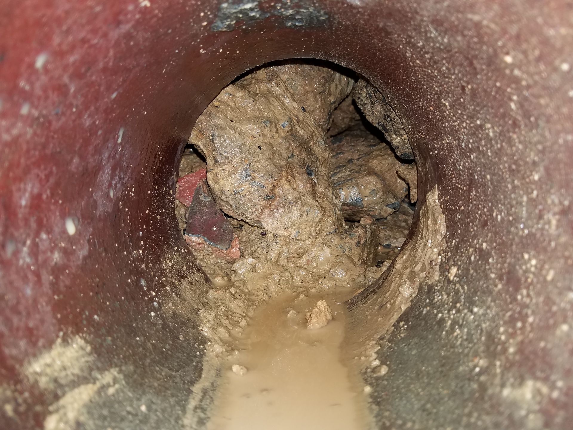 A close up of a drain with a lot of dirt coming out of it.
