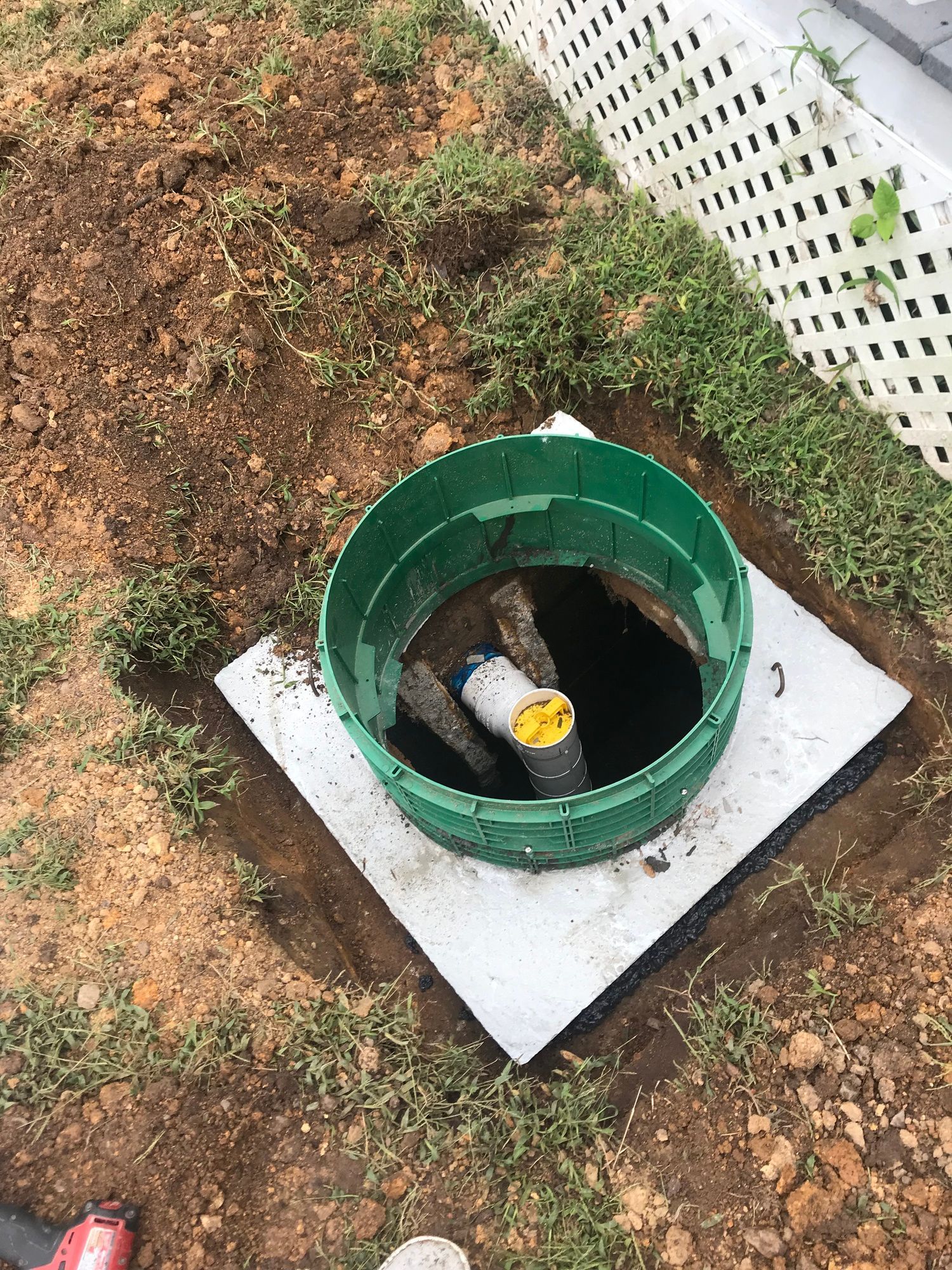 A green septic tank is sitting on top of a concrete slab.