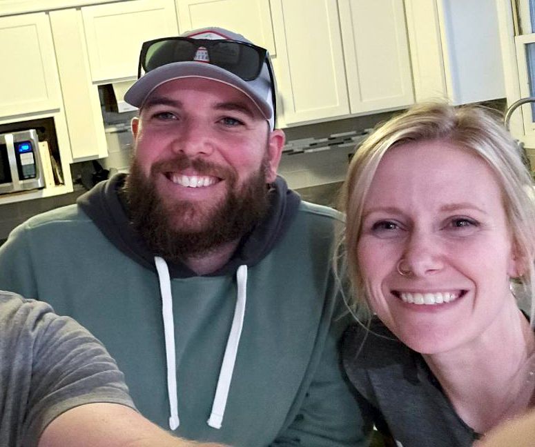 A man and a woman are posing for a picture in a kitchen.