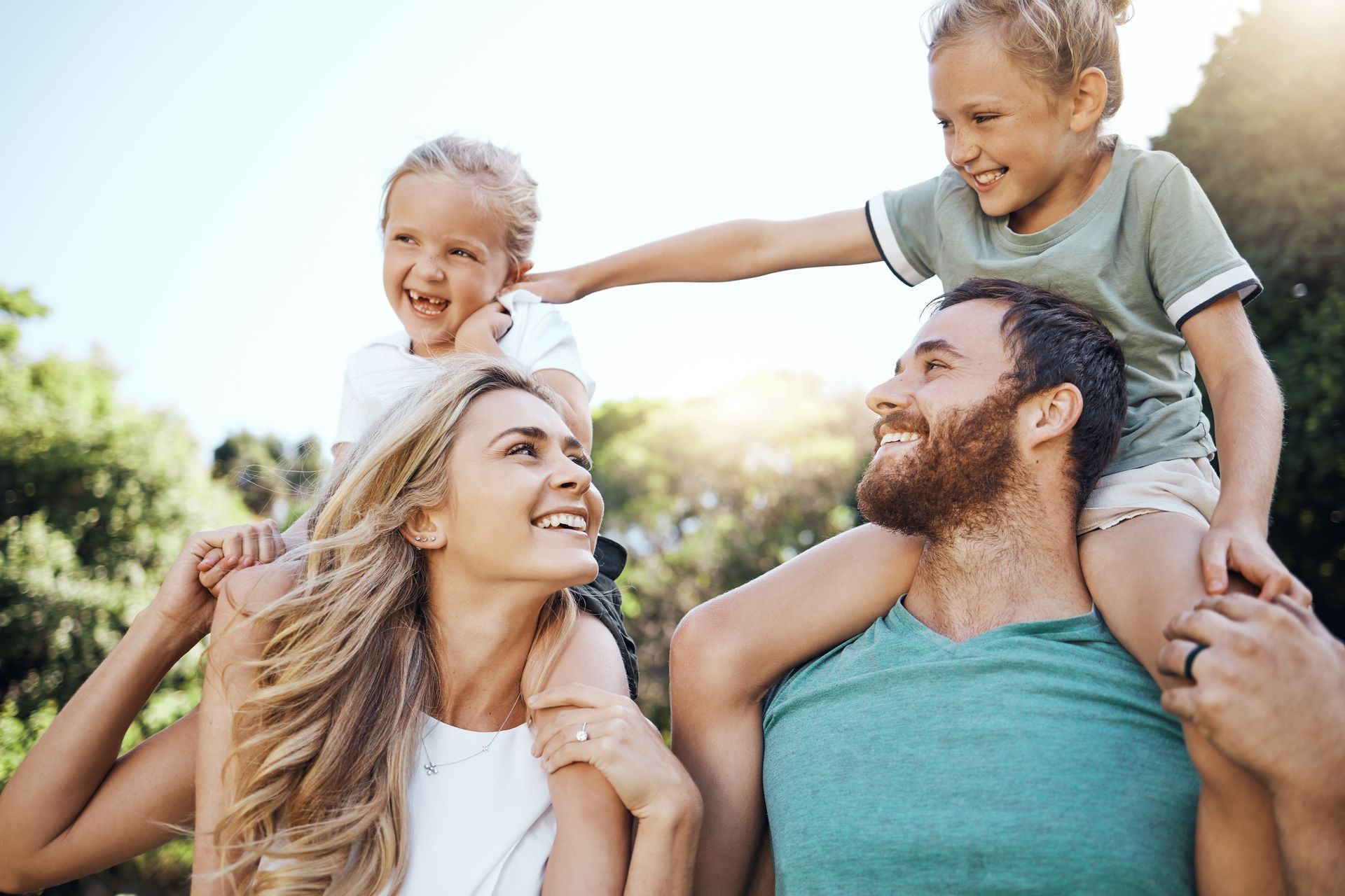 A man and woman are carrying two children on their shoulders.