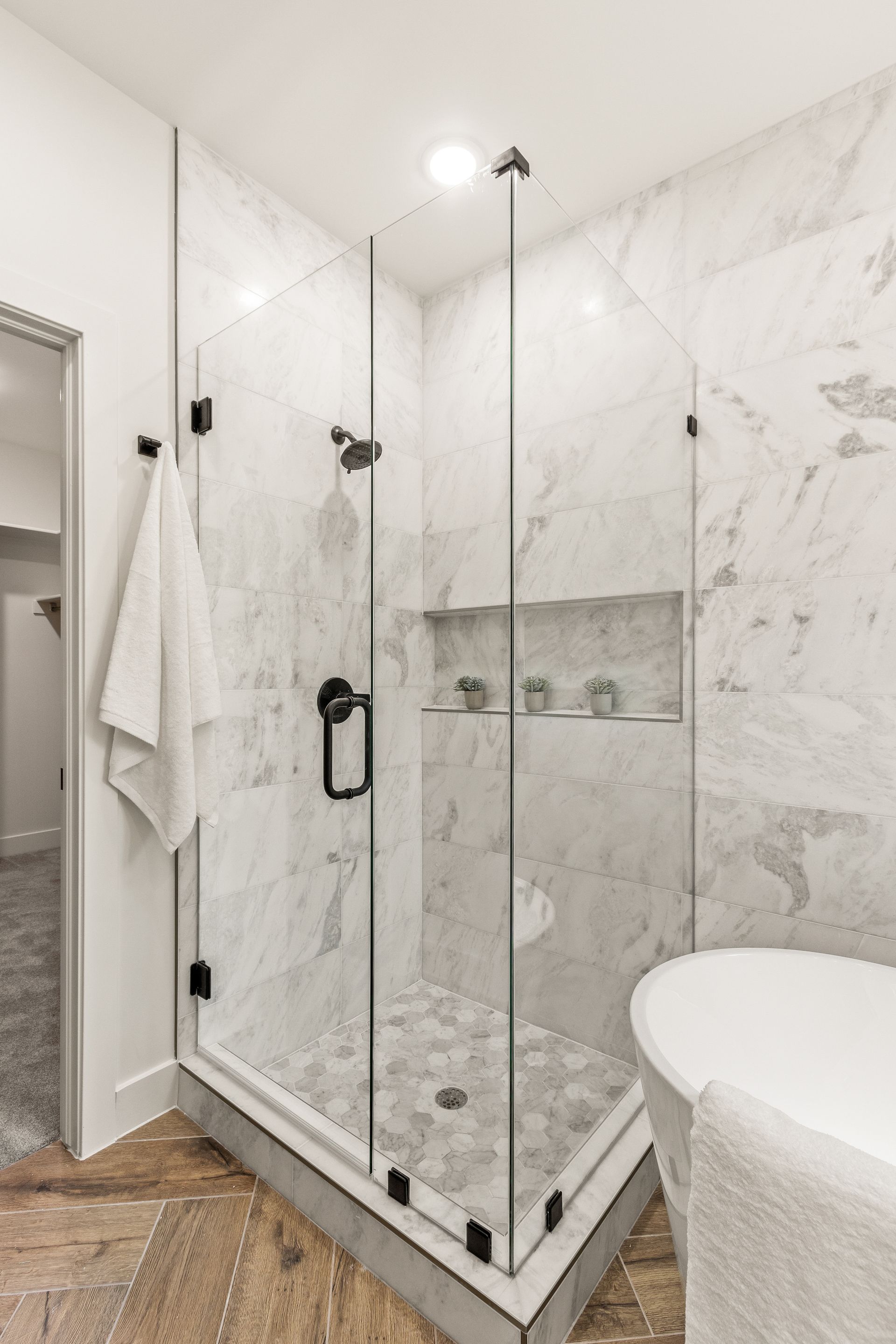Modern marble shower with glass doors and black hardware.