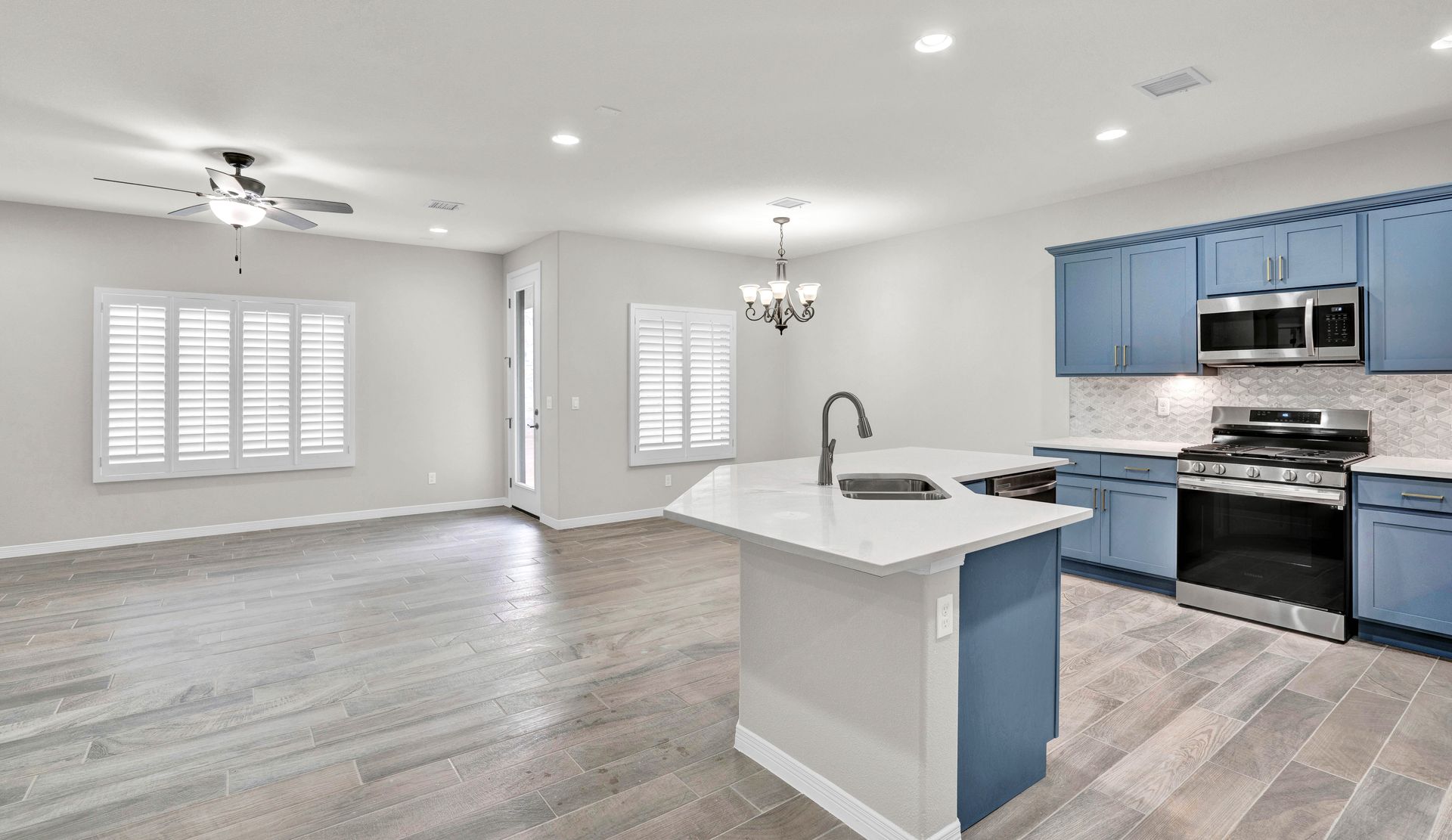 Spacious, open-concept kitchen with blue cabinets, white countertops, and wood flooring.