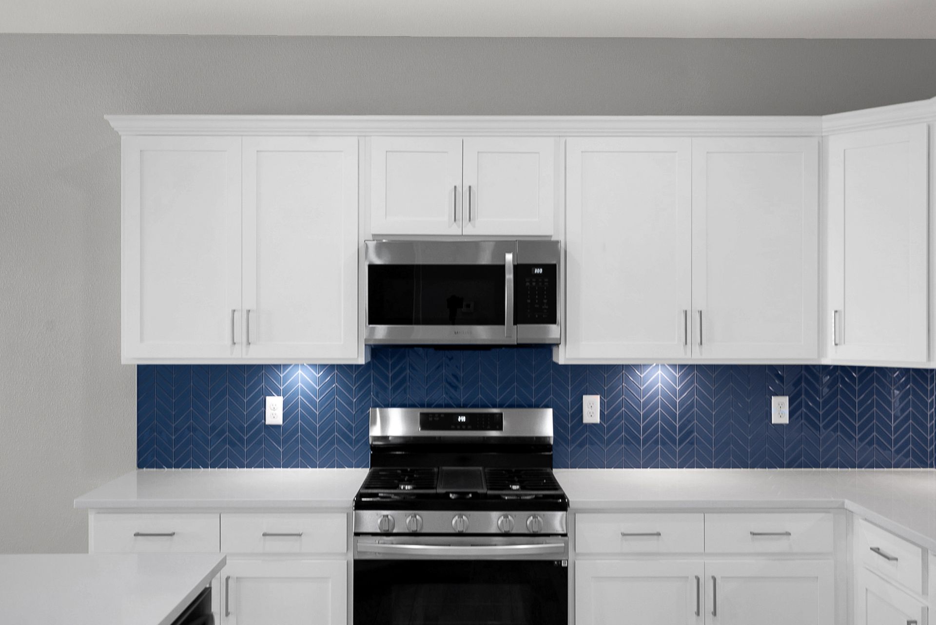 Kitchen with white cabinets, blue tile backsplash, stainless steel appliances.