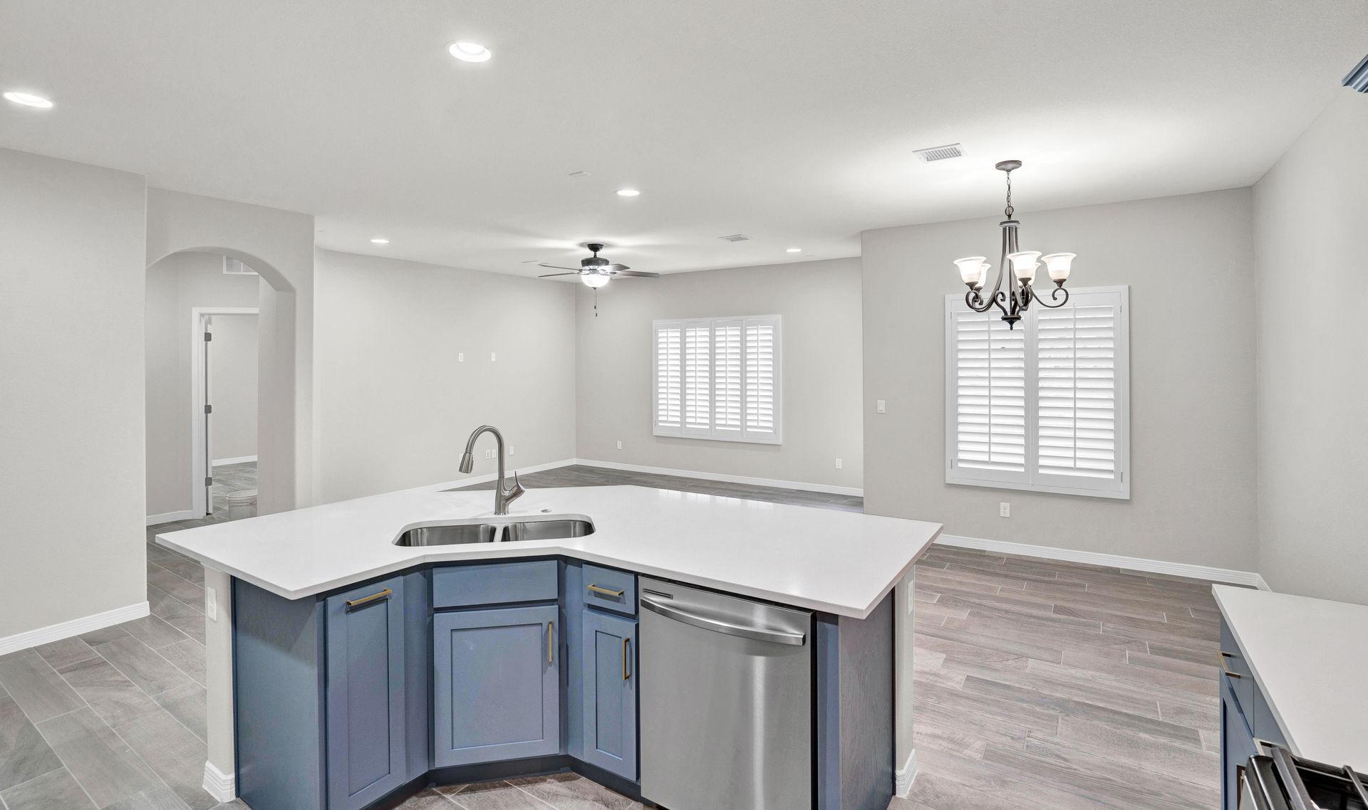 Modern kitchen with blue island, white countertops, and stainless steel appliances.