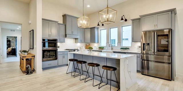 Modern kitchen with gray cabinets, white countertops, and a large island with stools.