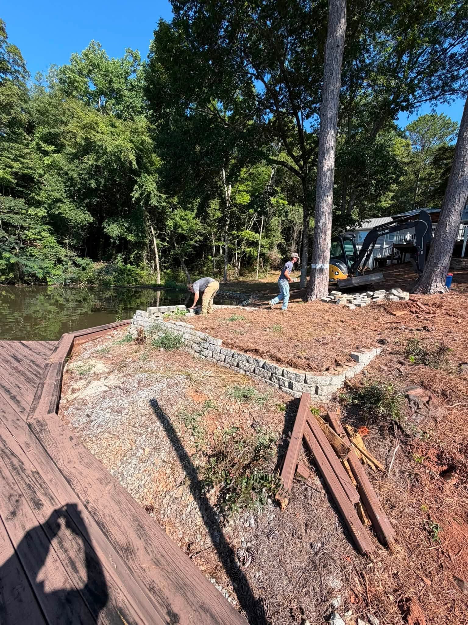 Two people on a rocky trail beside trees and a house on a sunny day