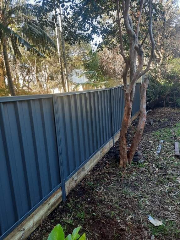 A Dark Grey Corrugated Metal Fence With a Wooden Base — A Betta Fence 'N' Yard In Wauchope, NSW