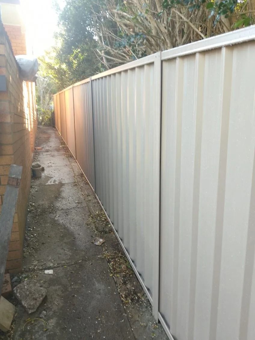 A Narrow Outdoor Pathway Between a Brick Building and a Tall — A Betta Fence 'N' Yard In Wauchope, NSW