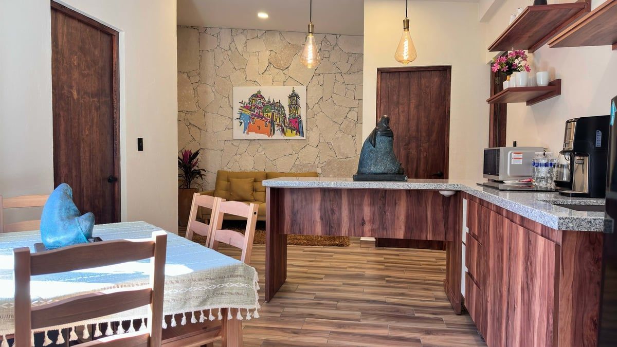 Modern kitchen-dining space with wood cabinets, marble countertop, dining table, and hanging pendant lights
