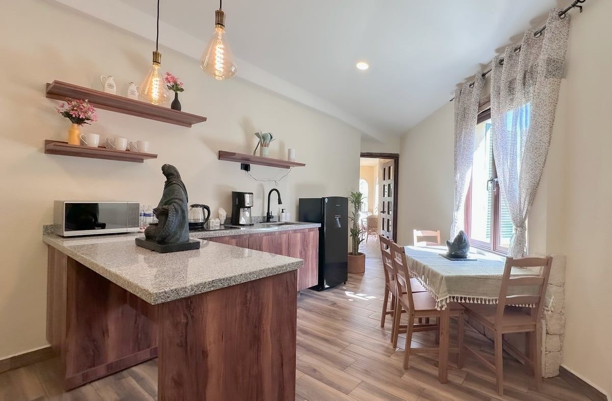 Bright kitchen and dining area with wood floors, island, dining table, and large windows with sheer curtains