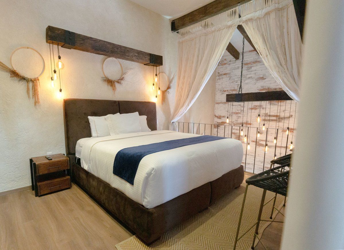 Cozy bedroom with white bed linens, brown accents, wall sconces, and sheer curtains by a window