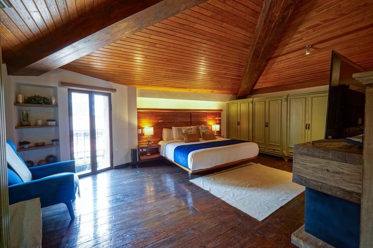 Cozy wood-paneled bedroom with a large bed, wardrobe, and balcony doors letting in natural light