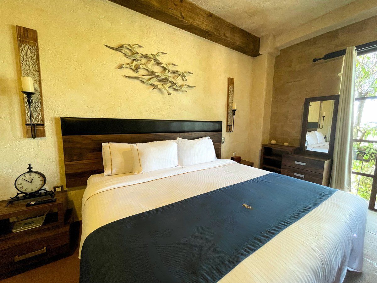 Cozy bedroom with a king bed, dark blue blanket, bedside tables, and a balcony view.