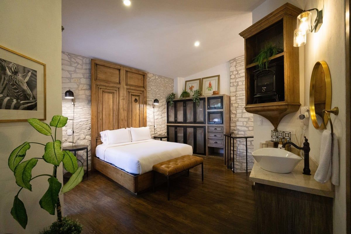 Cozy bedroom with white bed, wooden furnishings, brick accent wall, and soft warm lighting