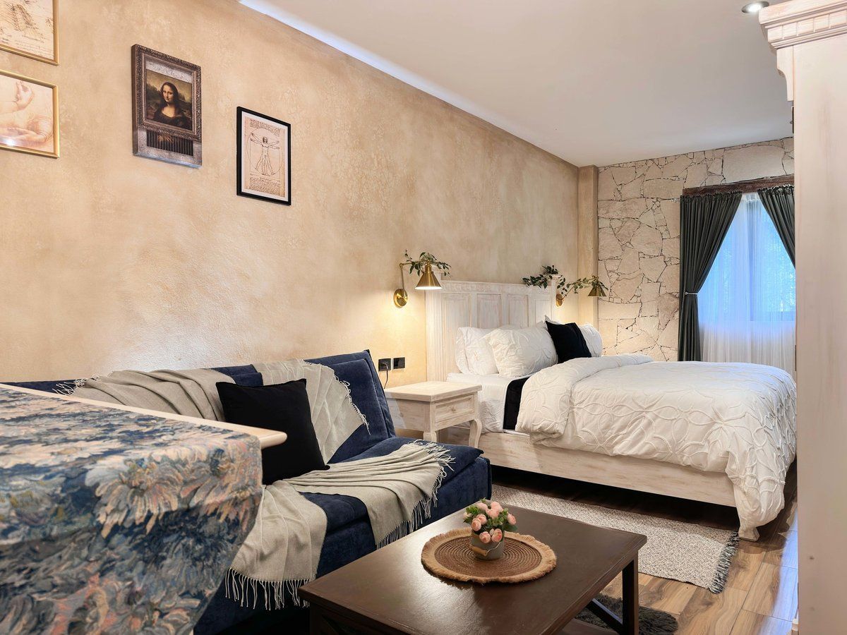 Small cozy bedroom with a white bed, blue sofa, and framed wall art
