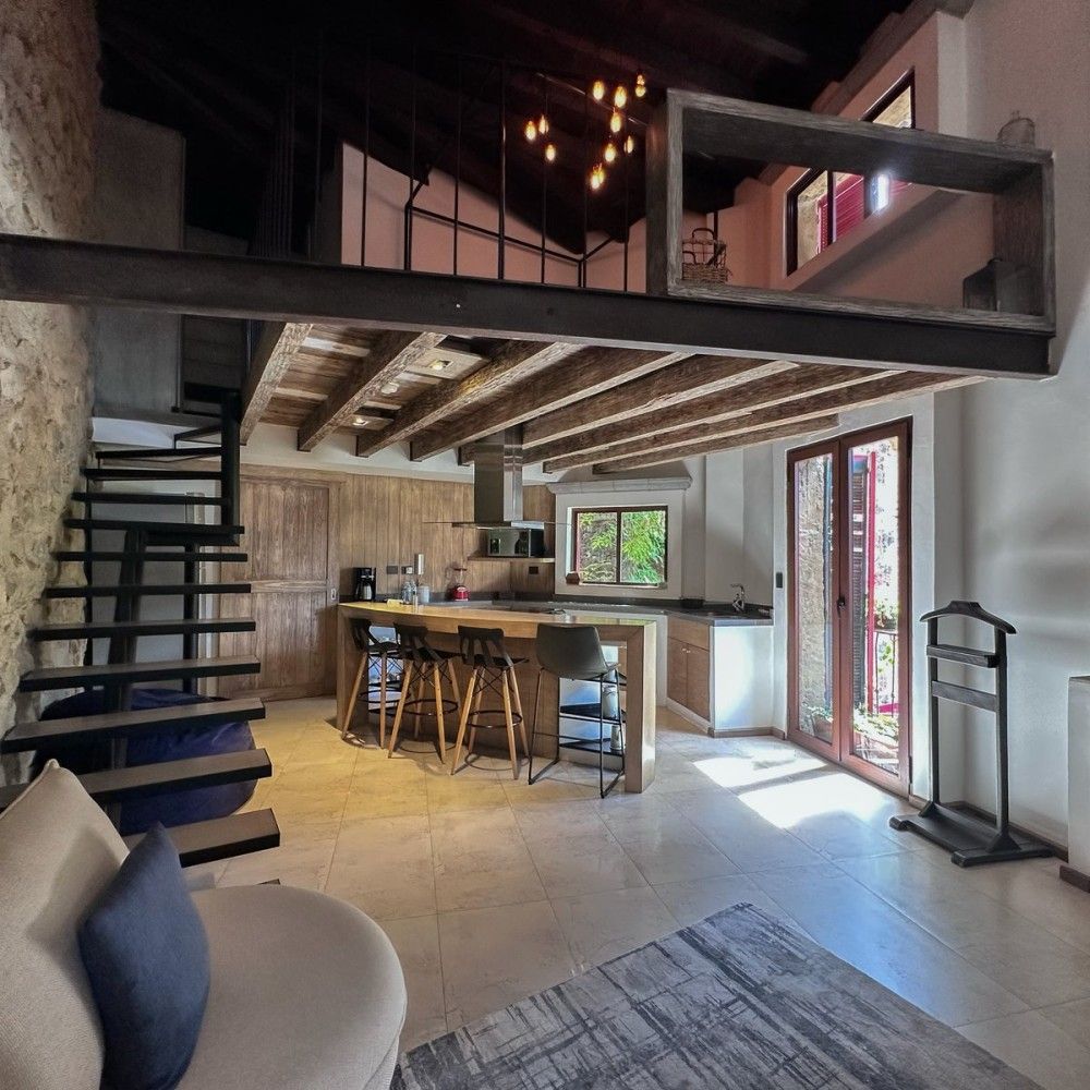 Modern loft interior with kitchen, staircase, mezzanine, and glass doors to outside