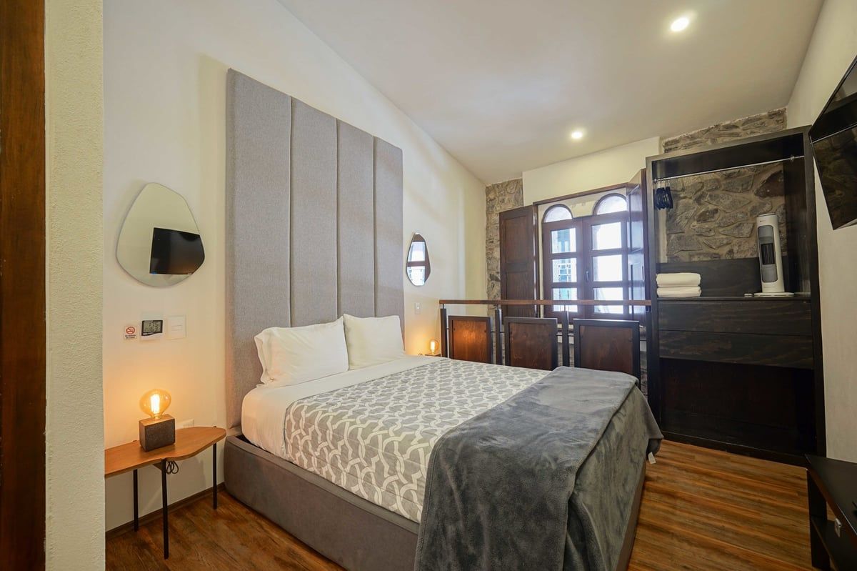 Cozy bedroom with a bed, bedside lamp, wooden floor, and windowed cabinet area