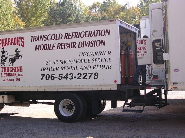 White mobile repair service truck with refrigeration advertising text parked outdoors