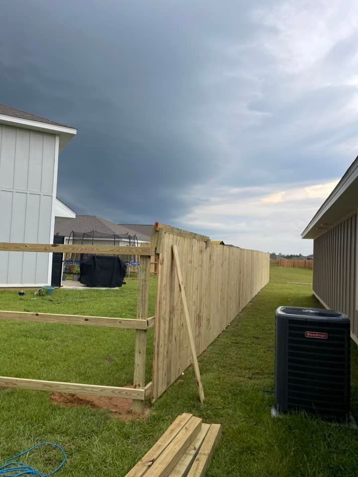 A wooden fence is being built in the backyard of a house.