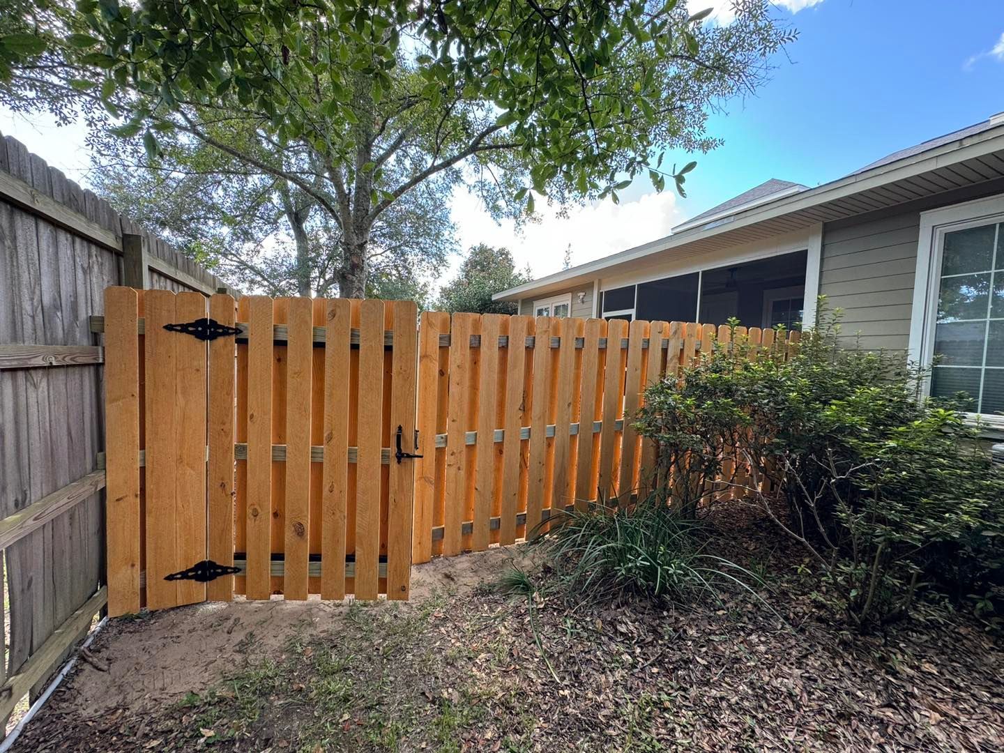 A wooden fence with a gate in the backyard of a house.