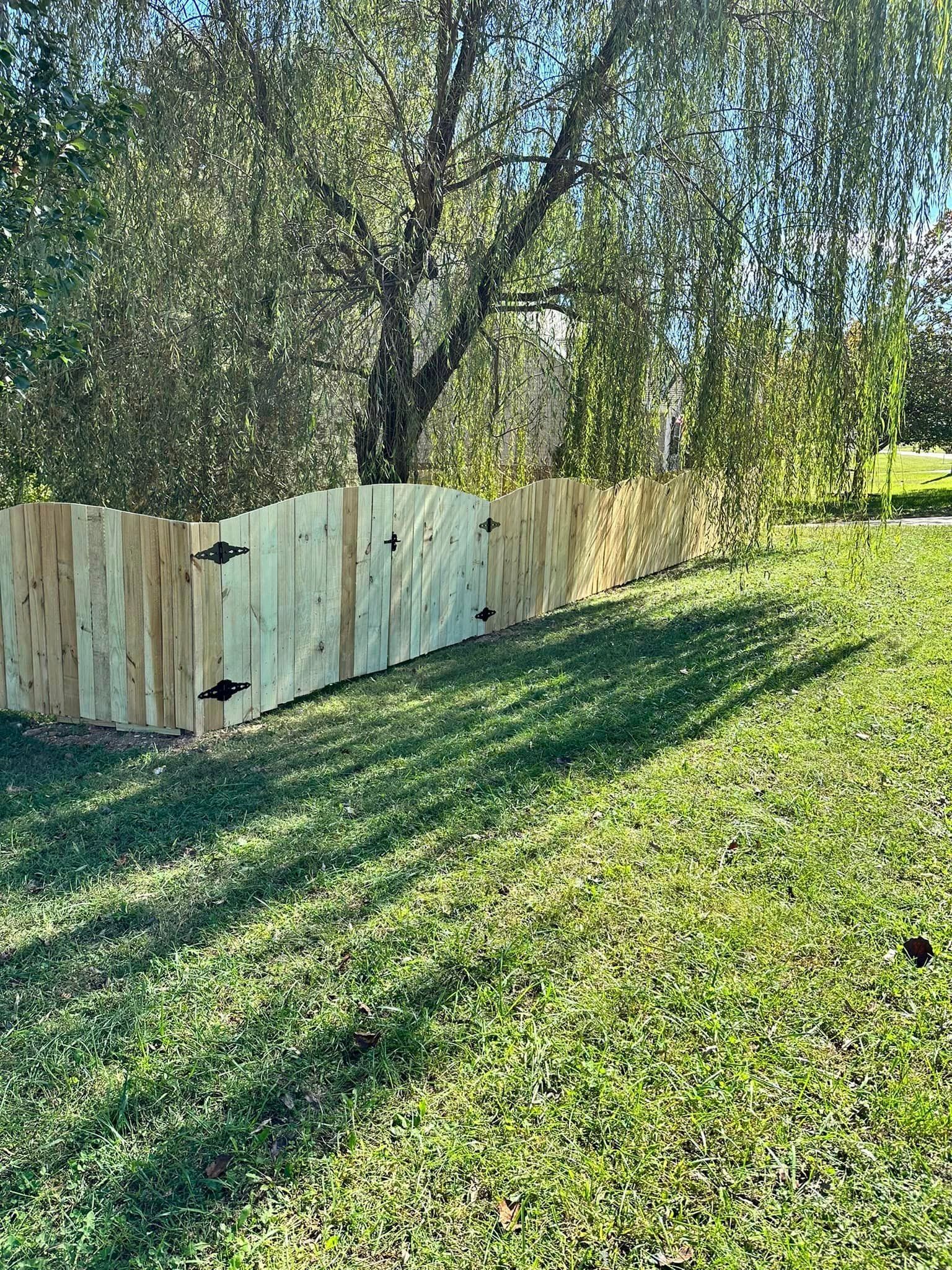 A wooden fence is sitting in the middle of a lush green field.