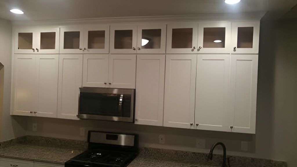 Modern kitchen with white cabinets, stainless steel microwave, and dark countertop.