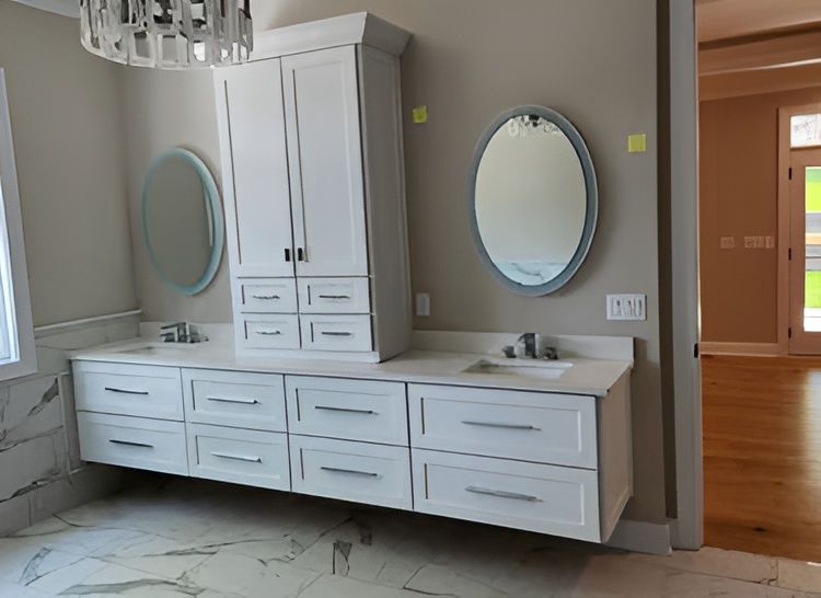 Modern bathroom vanity with white cabinets, double sinks, and two oval mirrors against gray walls