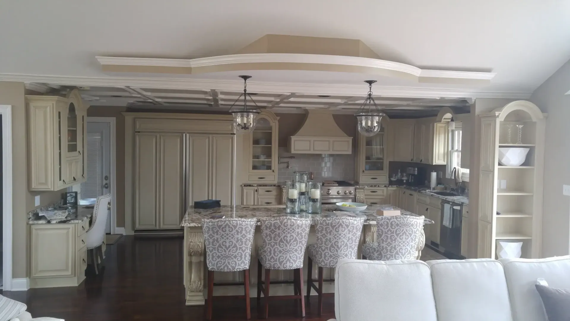 Open-concept kitchen and dining area with island, pendant lights, and patterned chairs near a living room.