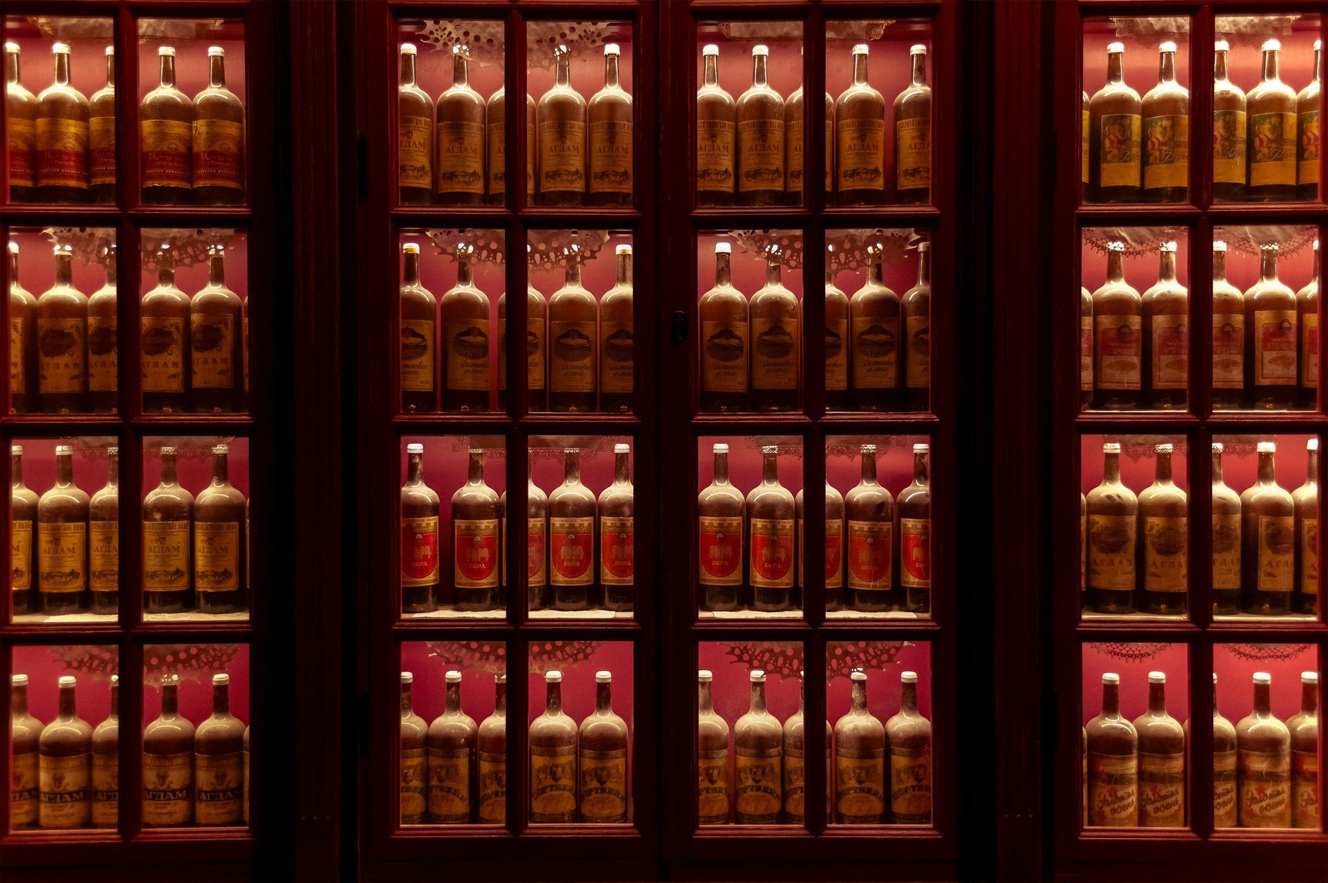 Rows of illuminated liquor bottles in glass cabinets against a dark background
