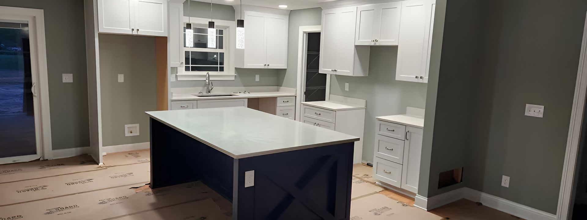 Modern kitchen with white cabinets, large island, gray walls, and built-in stainless steel appliances.