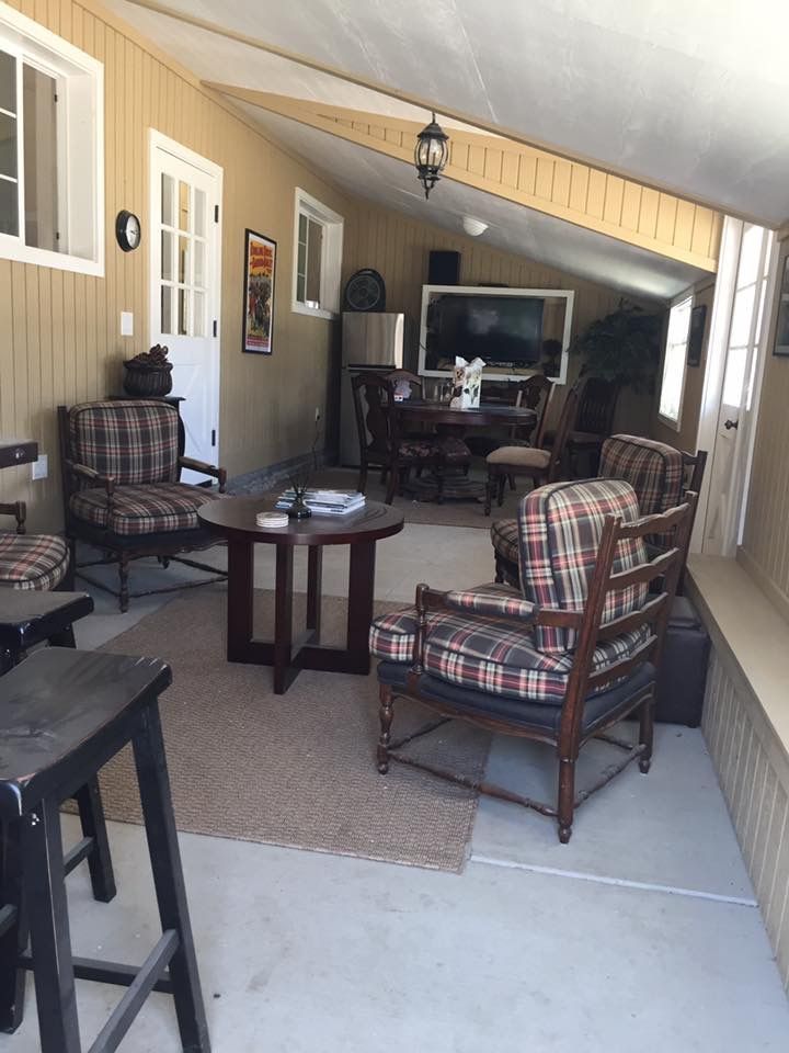Covered porch with wicker seating, small tables, and a TV at the far end.