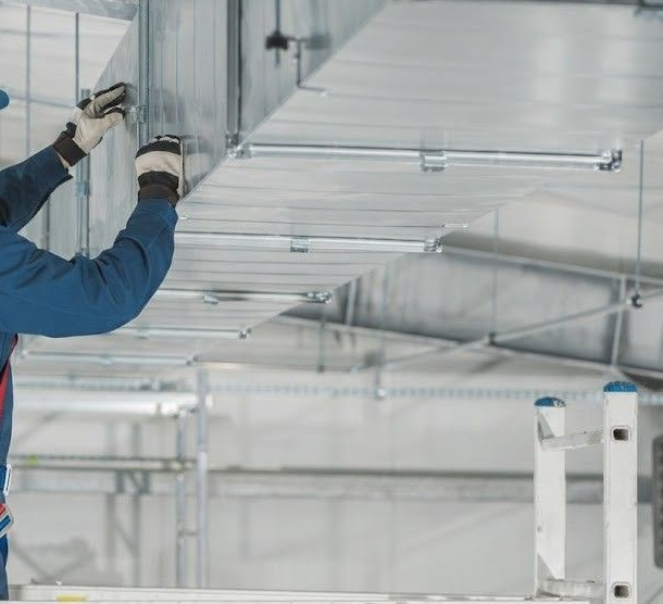 Worker installing metal ceiling panels in a bright industrial interior