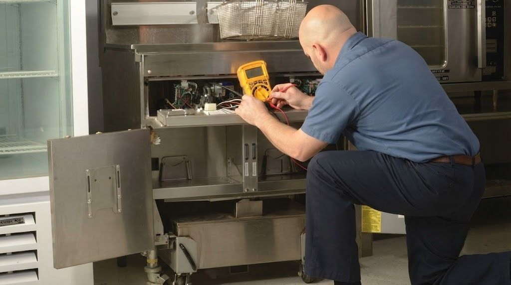 Technician inspecting open industrial equipment with a yellow meter in a workshop