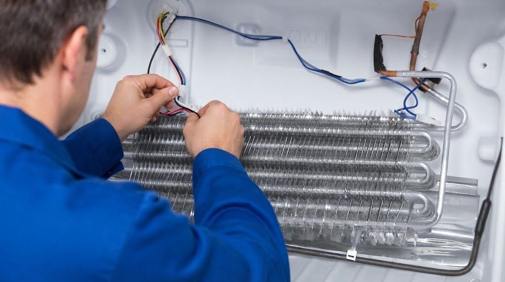 Technician in blue jacket repairing a large metal cooling unit with exposed wiring