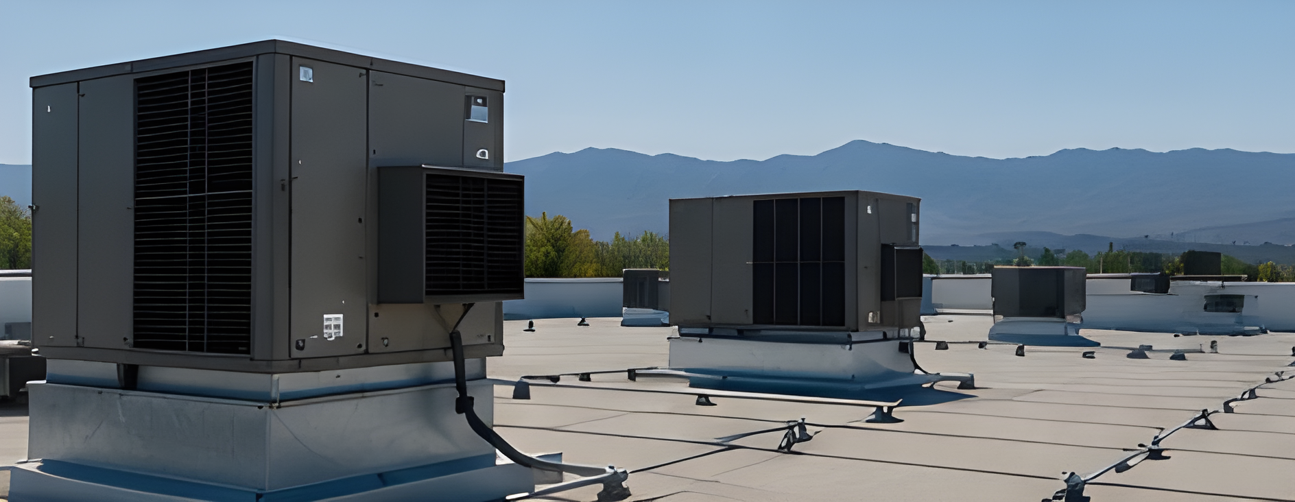 Rooftop HVAC ductwork and ventilation units under a clear blue sky, with a distant city view