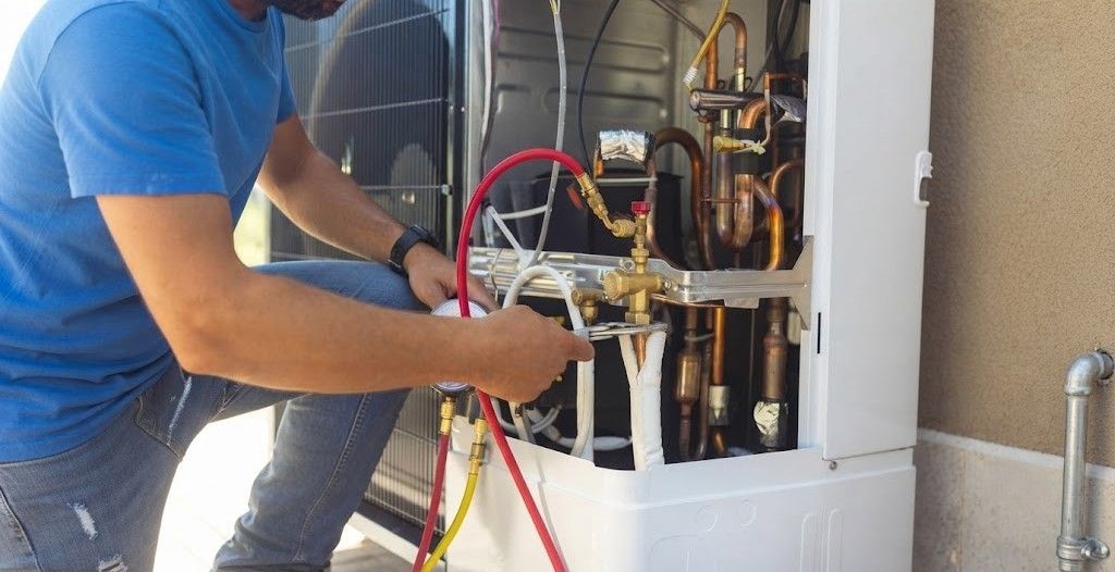 Technician adjusting HVAC unit with tools and colored hoses inside a utility room