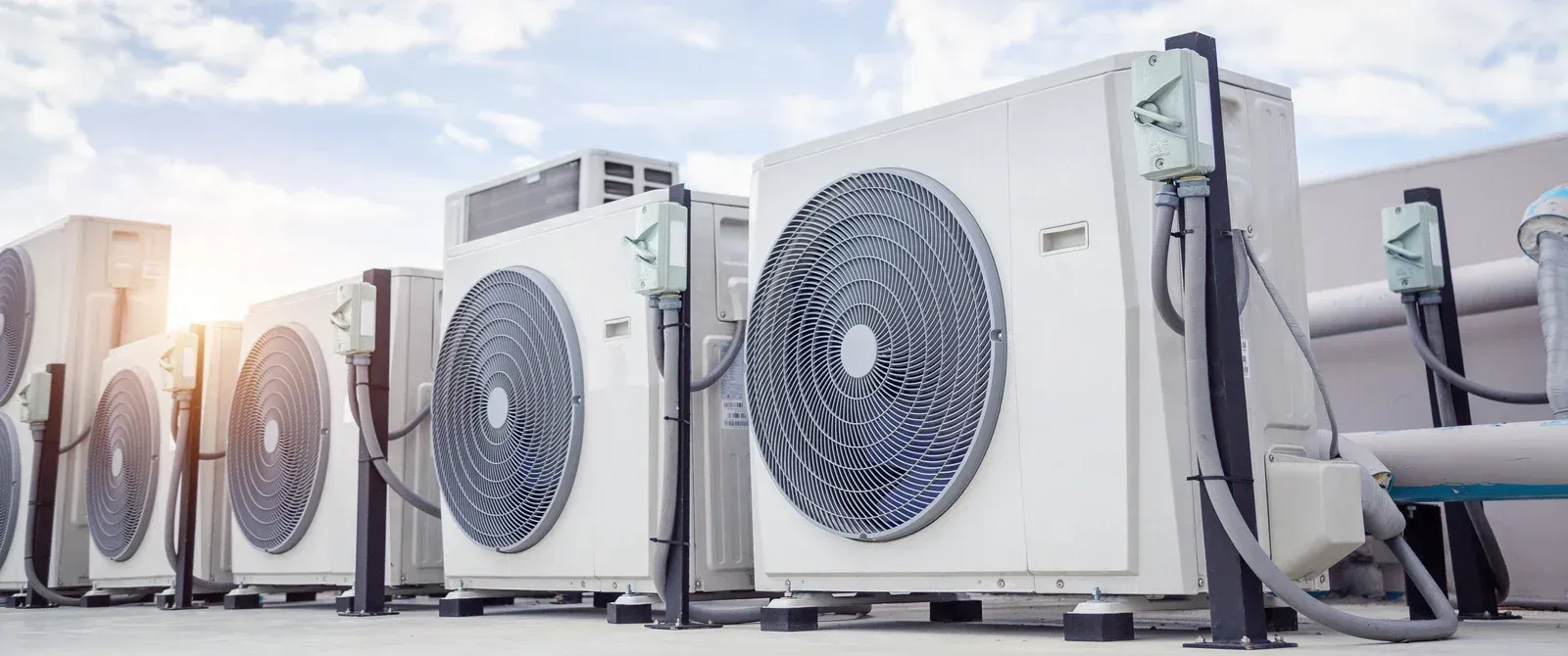 Row of outdoor HVAC units with large fans on a rooftop or industrial platform