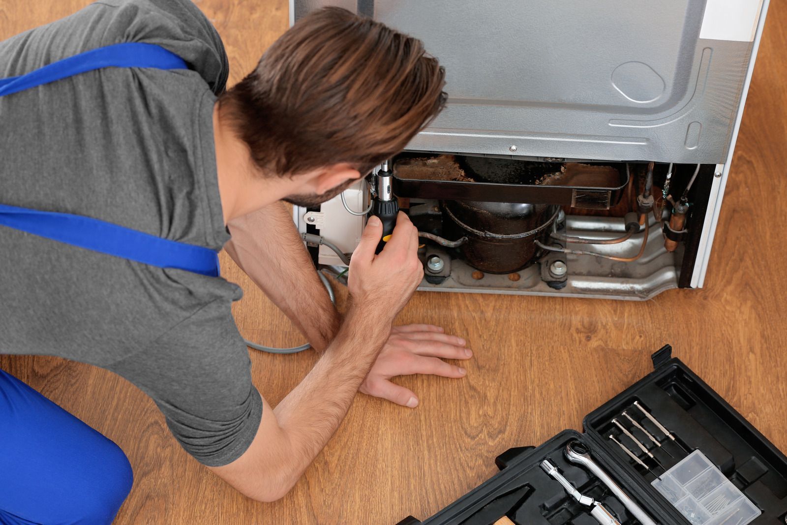 Technician tightening an HVAC unit connection with a wrench outdoors