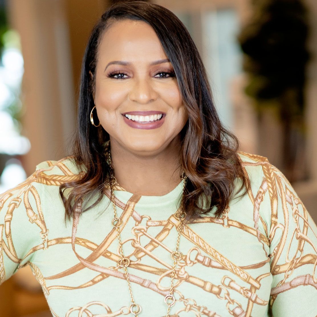 A woman in a green and gold sweater is smiling for the camera.