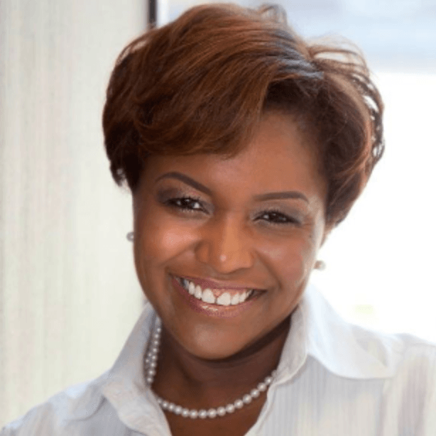 A woman wearing a white shirt and a pearl necklace smiles for the camera