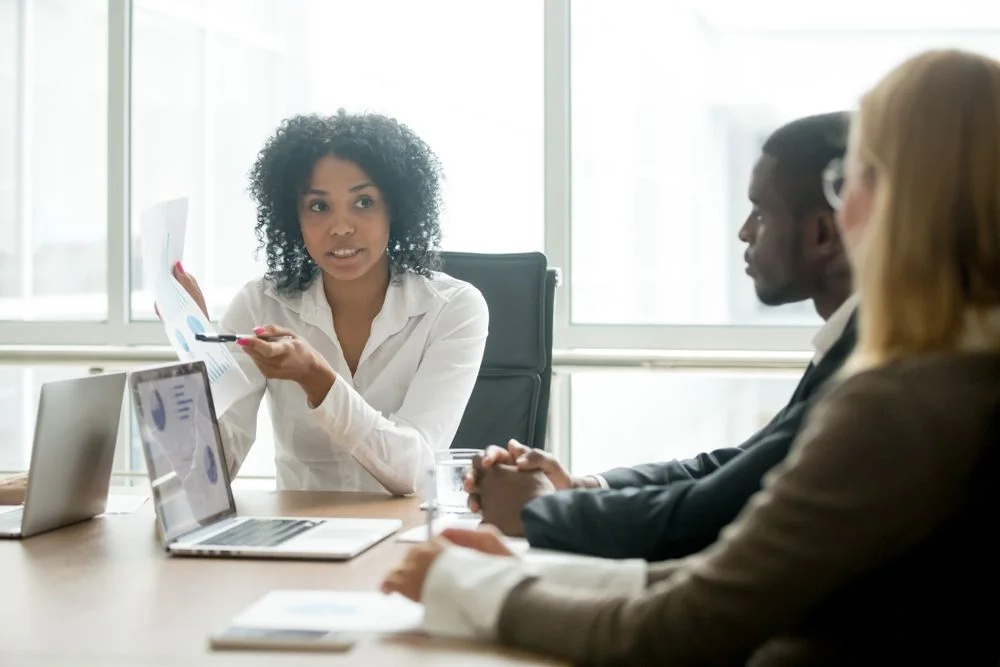 A woman is giving a presentation to a group of people at a conference table.